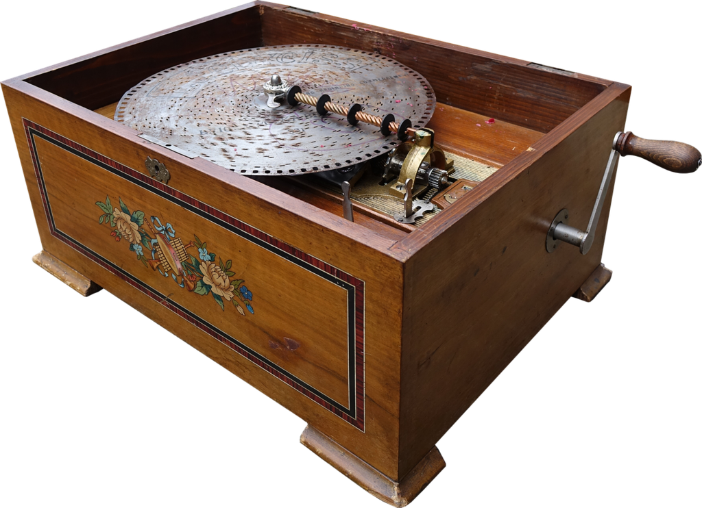 A vintage wooden music box with a large metal disc and hand crank, decorated with a floral inlay on the side panel.