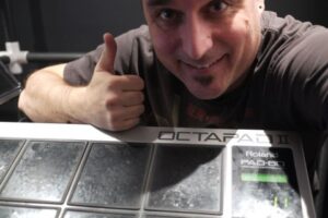 A person smiles and gives a thumbs up while posing with a Roland OCTAPAD II electronic percussion pad.