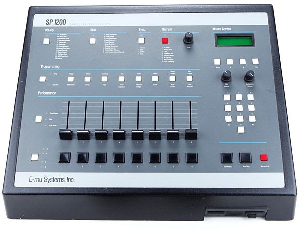 A vintage E-mu SP-1200 drum machine and sampler with numerous gray and black pads, sliders, and buttons, a small display screen, and labeled sections for programming and performance.