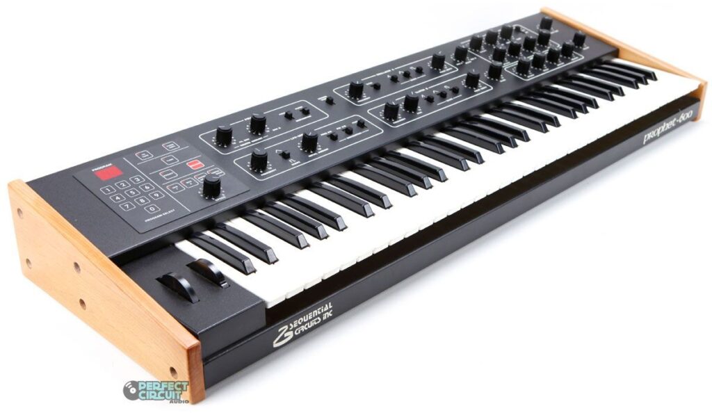 A black analog synthesizer keyboard with wooden side panels, several control knobs, sliders, and buttons on the top panel. The brand Sequential Circuits is visible on the side.