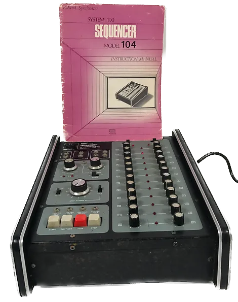 A vintage Roland System 100 Model 104 sequencer with multiple knobs and switches, positioned in front of its pink instruction manual titled Sequencer Model 104.