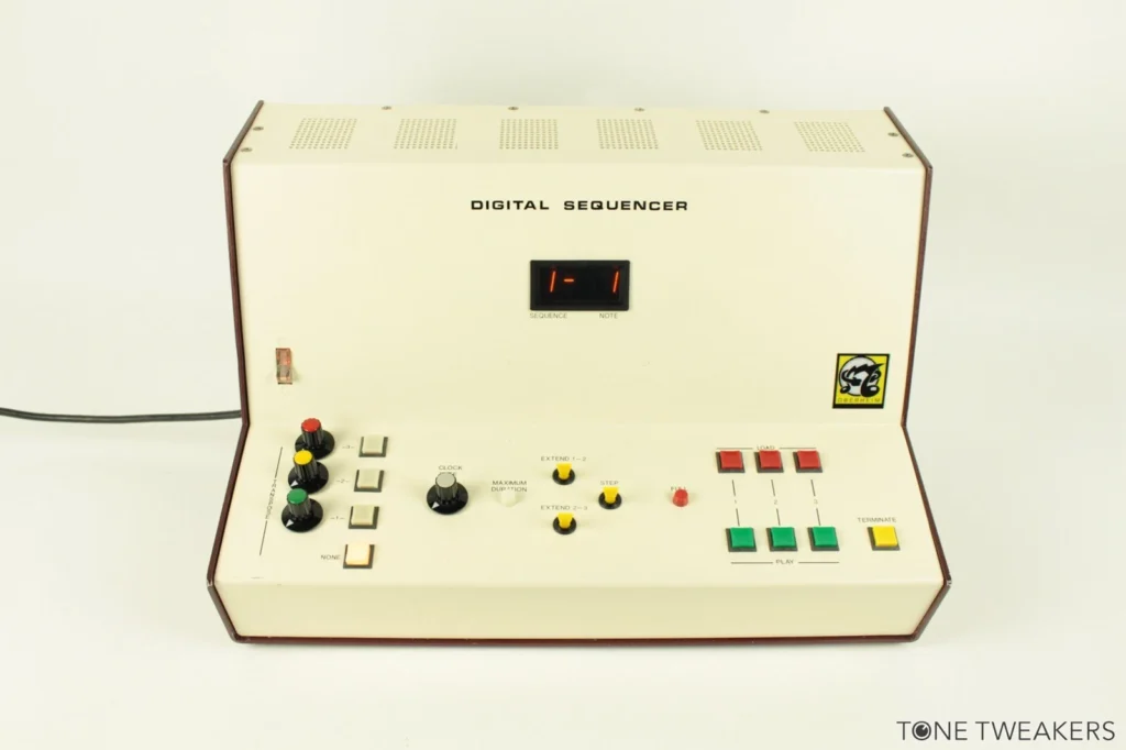A vintage digital sequencer with a cream-colored panel, various knobs and switches on the left, buttons on the right, and a small digital display showing 1 at the center. The unit is labeled DIGITAL SEQUENCER.