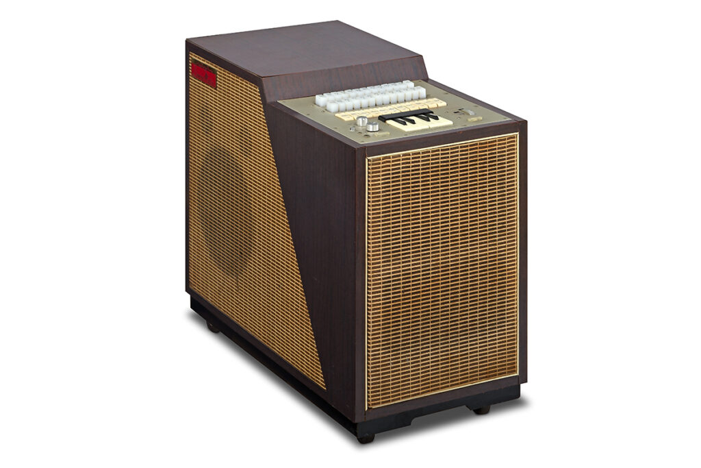 A vintage electronic organ with a wood finish, yellow grille, a panel of white switches, and black-and-white keys on top, placed on a white background.
