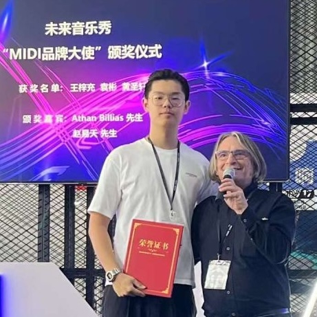 Two people stand together smiling on stage, one holding a red certificate. Behind them is a purple digital backdrop with Chinese text and the words MIDI 品牌大使 and Athan Billias.