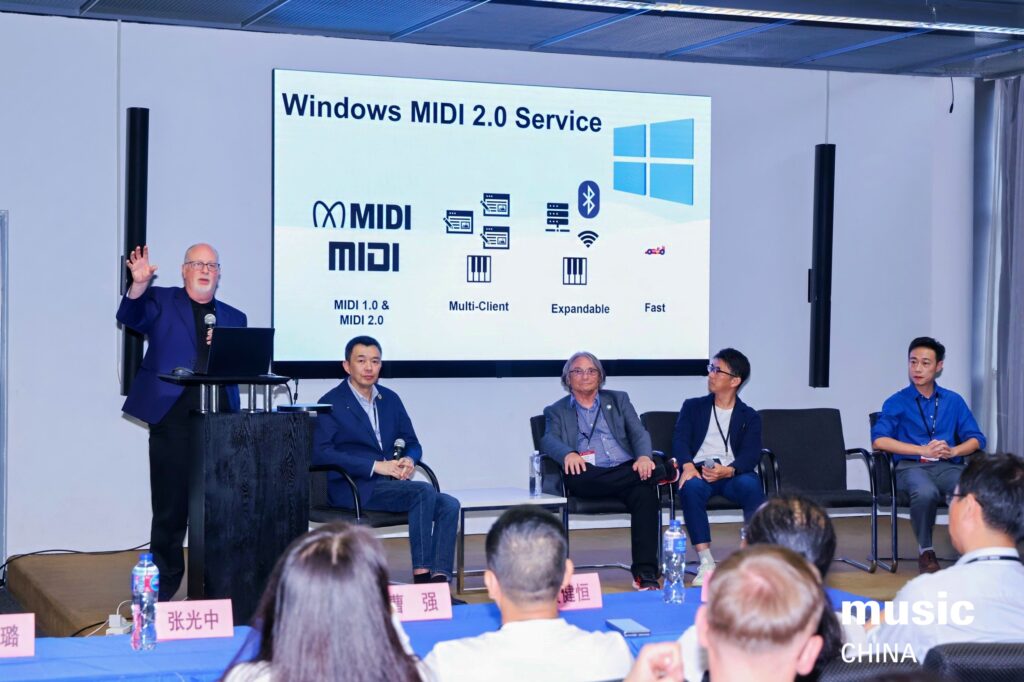 A speaker presents at a conference, gesturing toward a screen displaying Windows MIDI 2.0 Service features, while four panelists sit beside him. The audience and music CHINA logo are visible in the foreground.