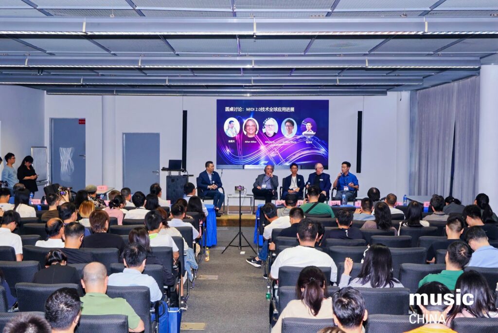 A panel of five speakers sits onstage in front of a large audience at a conference. A screen behind them displays their photos and names with text in Chinese. The event branding reads music CHINA.