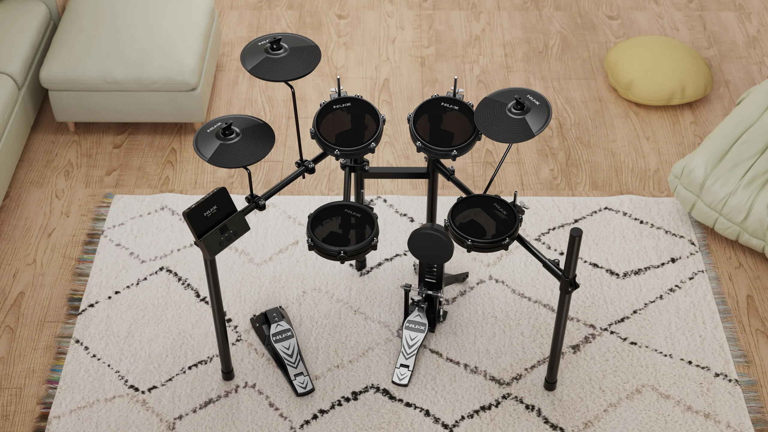 A black electronic drum set with four drum pads, three cymbals, and two pedals sits on a white patterned rug in a living room with wooden floors, a beige sofa, and a yellow cushion.