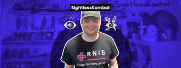 Sightless Kombat wearing a black cap and an RNIB Design for every gamer t-shirt stands in front of a blue background with the text SightlessKombat and gaming icons above their head.